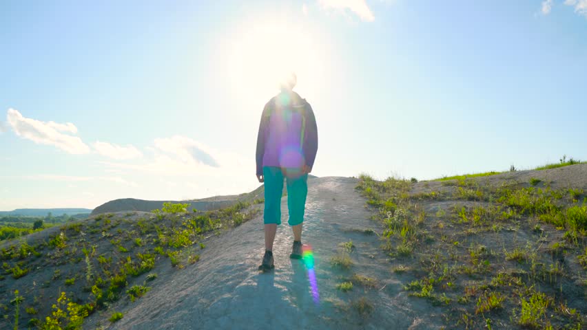 Woman is traveling with a backpack over hilly terrain. Hiking