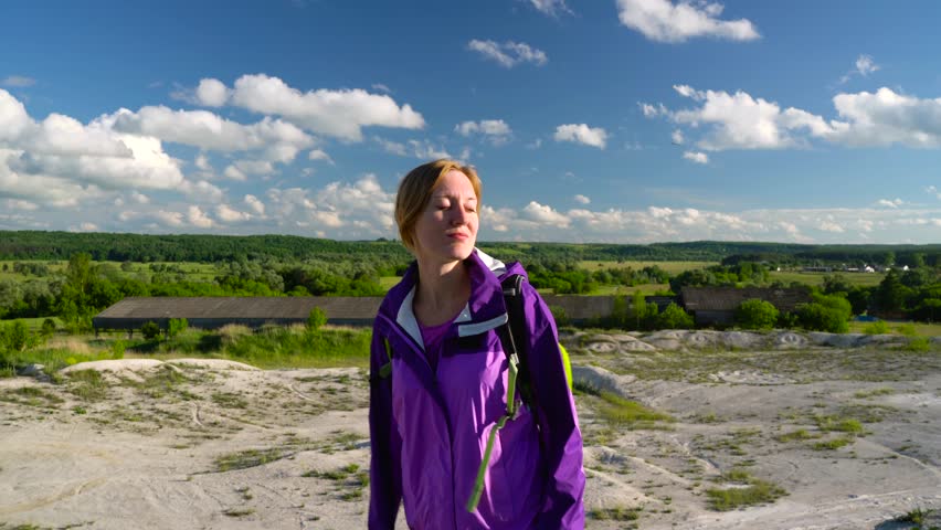Woman is traveling with a backpack over hilly terrain. Hiking