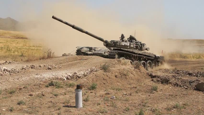 Tank-T72 on the test site in the desert area overcomes a long line in its path and slowly climbs on the edge picking up a column of dust behind you. The video was filmed by a  military videographer.