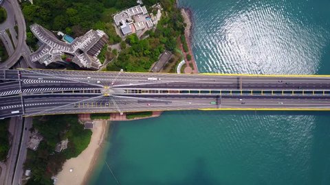 Beautiful top-down shot of traffic on modern cable stayed bridge. Rambler channel bright blue-green water with shining waves under the road. Aerial view of Ting Kau Bridge at Hong Kong.