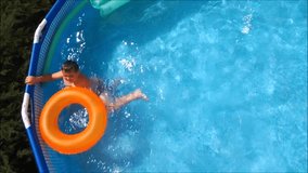 Little Boy Swimming In Pool on orange inflatable rubber ring.