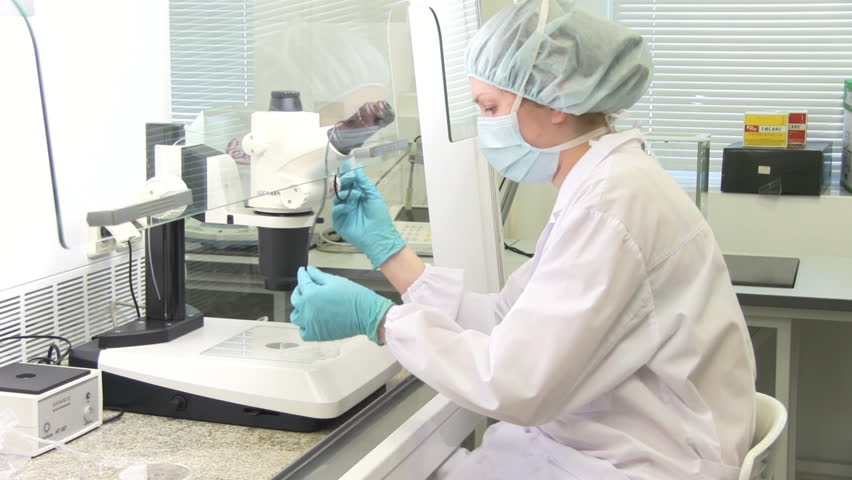 woman looking through microscope in laboratory