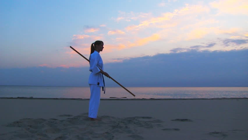 young woman training karate on sunset beach