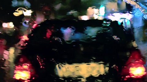 Night city traffic through wet window. Focus on windshield rain drops. Video Stok