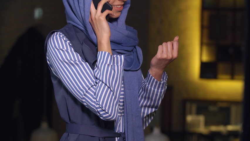 Muslim woman smiling talking on a cell phone