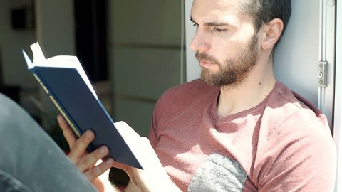 Handsome man finish reading book and relaxing on the balcony, steadycam shot
