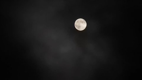Clouds float across the sky and close the moon