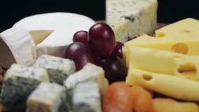 Cheese platter with nuts and grapes on the table. Rotation video.