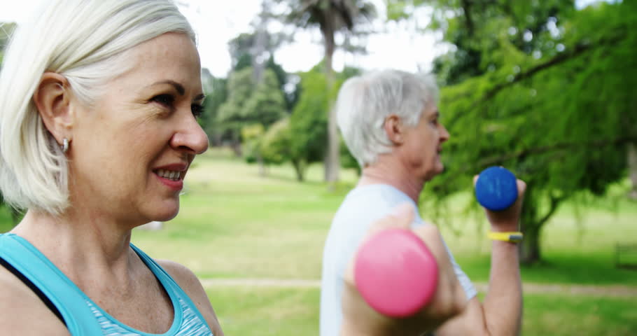 Active senior couple excercising with dumbbells in the park