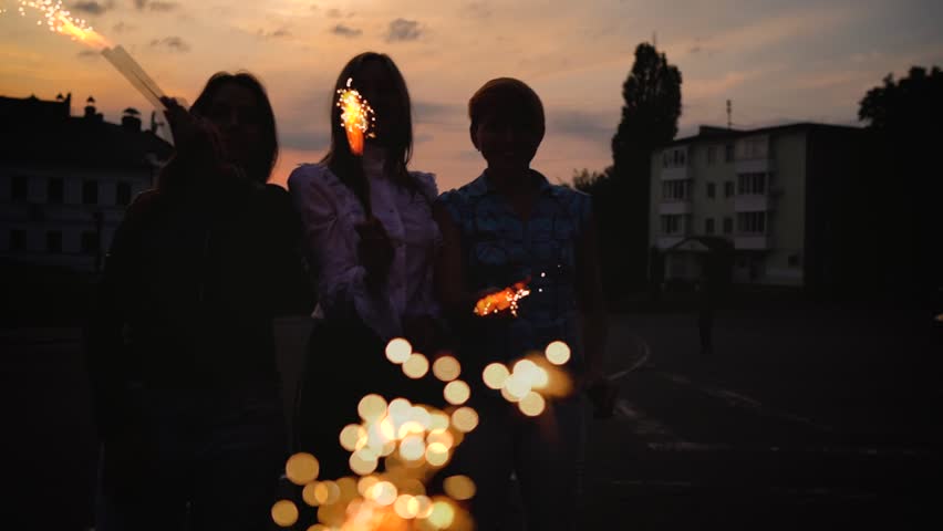 Three female friends having fun and playing with firework candles