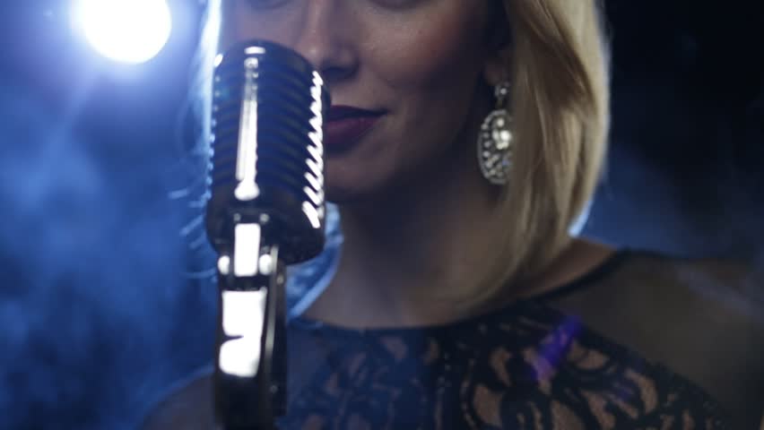 Pretty young woman, jazz singer with microphone. Shallow depth of field. Only lower part of face shown with lips