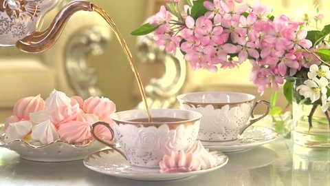 Tea Pouring. Porcelain cup of Healthy Tea closeup. Antique porcelain, luxurious interior. Slow motion video footage 240fps 