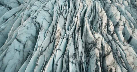 Aerial top view of the ridges of white glacier with black ash. Scenic iceberg in national park in Iceland.