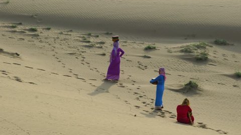 Phan Rang city, Viet Nam - May, 2017:  Cham women in traditional dress walking across sand dunes to collecting water near Phan Rang, Vietnam. Many Cham people retain, Ninh Thuan province