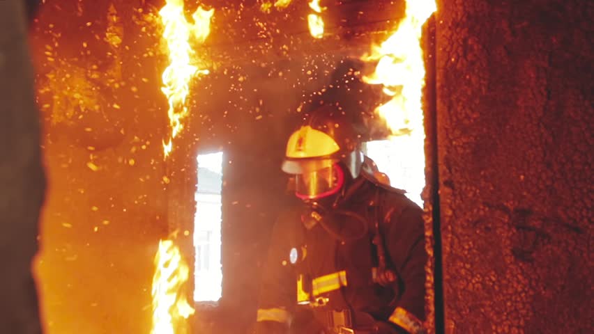 Three brave rescuers knock out the burning door and run into the smoke in the fire engulfed room. Raging fire