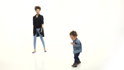 African american mother claps her hands and her son dances. White background Slow motion