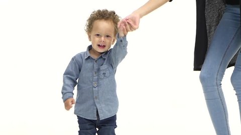 Kid holds his mother's hand and dances with her. White background. Slow motion