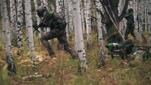 A player in paintball runs in the forest. Slow-motion shooting of 240 frames. Tactical game of paintball.