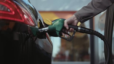 Multiple shots of a gas pump inserted in car tank. Slow motion.