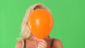 Closeup of young blonde woman and orange helium balloon popping - Powered by Shutterstock - Get 15% off with code: PIKWIZARD15