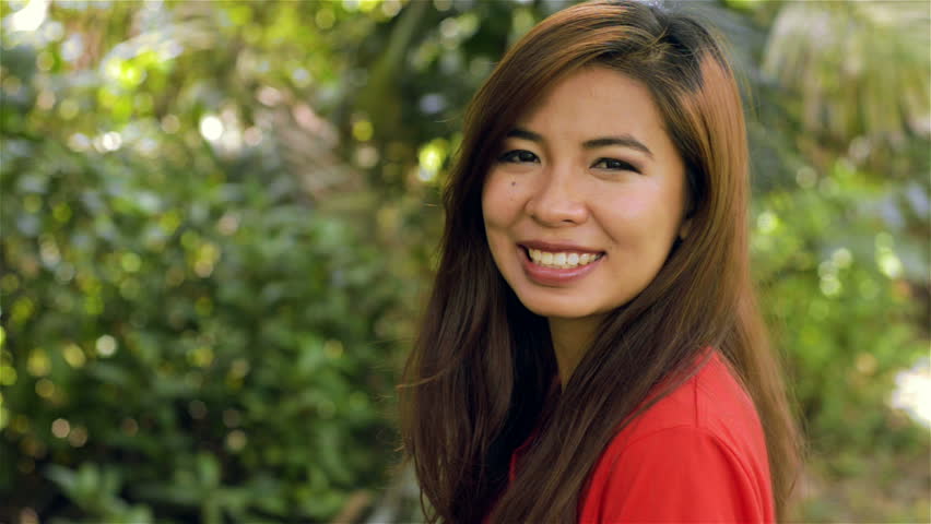 Young Asian woman turning to face the camera and smiling - dolly shot.