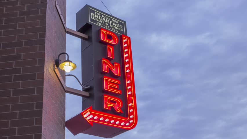 A Medium 4K Timelapse Shot of a Neon Diner Sign Pointing to a Cafe Illuminated Red in front of Beautiful Afternoon Clouds Royalty-Free Stock Footage #27990277