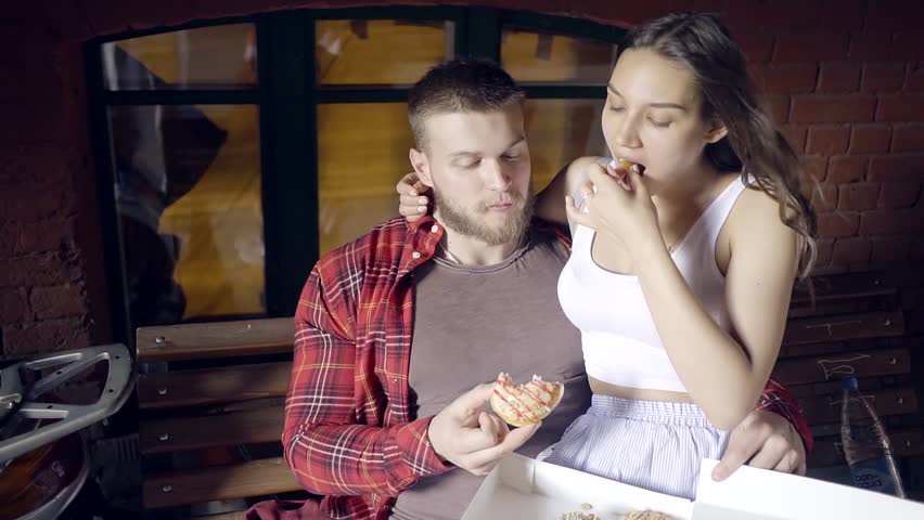 American young family eats a lot of doughnuts sitting on a city street.
