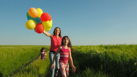 Happy family in nature with balloons. Mom with children in a field with balloons.