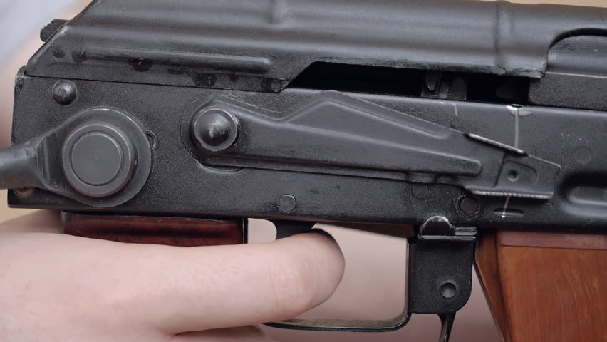 Male hands holding a machine gun. Switching firing mode of the gun.