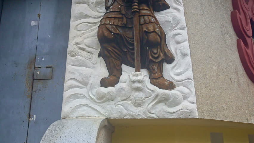 closeup large golden soldier with sword on white gyps panel bas-relief on building wall in monastery park in Vietnam