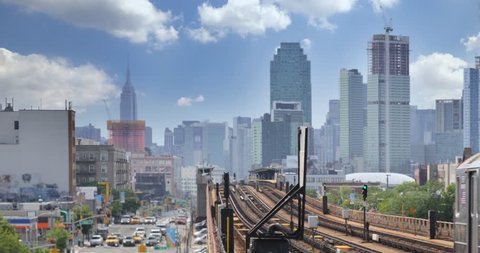 A view of the Manhattan skyline as seen from an elevated subway platform over Queens Boulevard in Queens.  	Empire State Building in the distance.