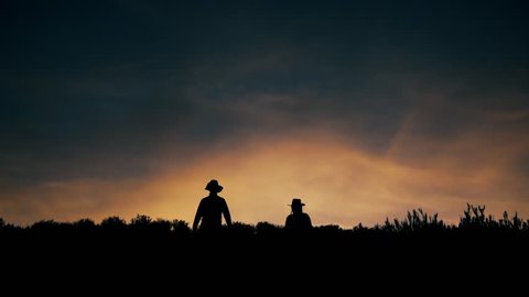 Silhouette of men walking down the hill against the sunset, Bolivia