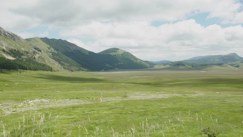 Green mountains and huge meadow on plateau in summer in Italy, 4K