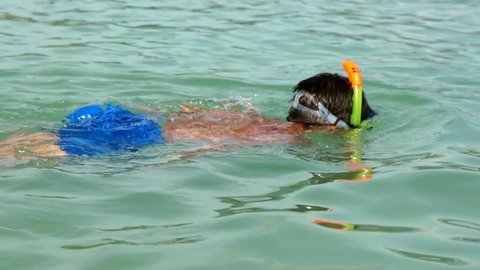 Young boy in the mask for diving swims in tropical sea