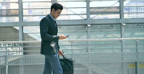 A young handsome businessman (student) in a suit, comes with a briefcase, at station, airport. Concept: a new business, traveling the world, communication, contacts, a new deal, phone, communications.