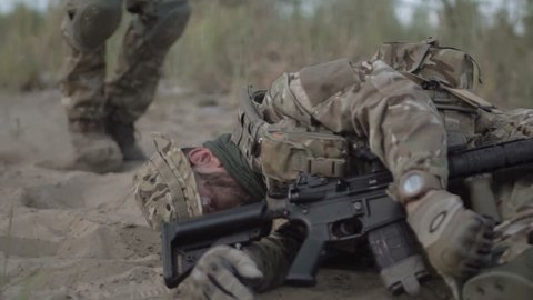 Slow motion the soldier saves getting injured while shooting and having contact on battlefield.