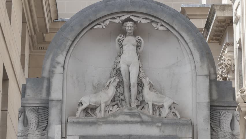 Statue of a woman on the wall of an old building.