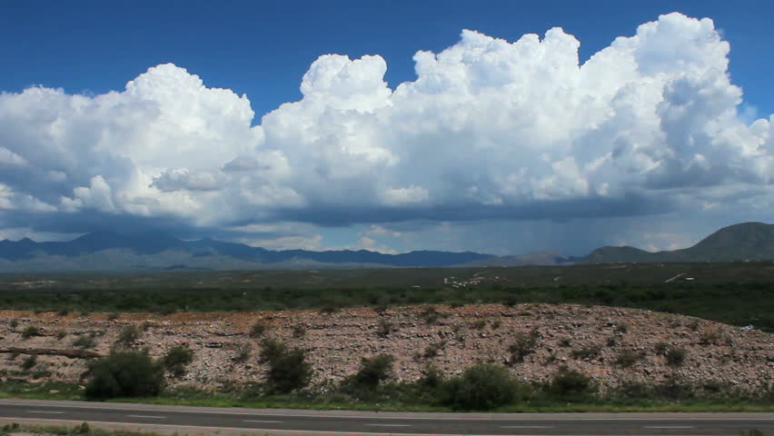 Time Lapse, Cars, trucks zip along American highway as thick, cloud mass swirls around mountains, creates beautiful, scenic background. 1080p