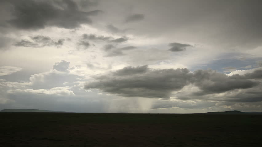 Time lapse of dark clouds moving overhead the  Serengeti plains .