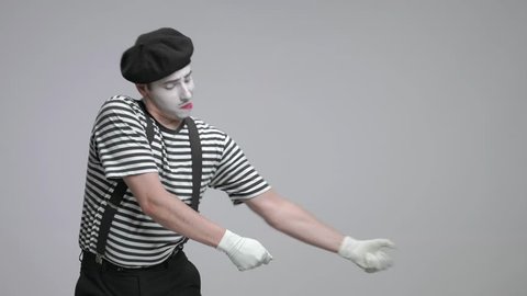 Mime pulling an imaginary rope isolated on gray background