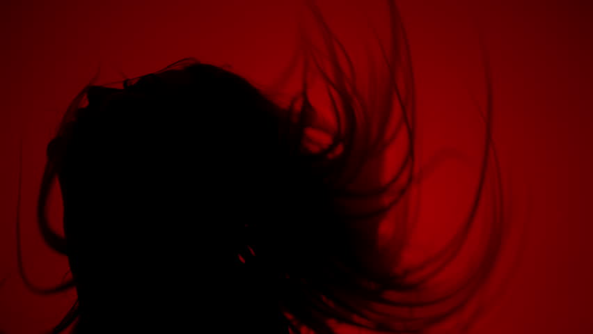 Silhouette of woman shaking hair on red background. Sexy girl silhouette in dark. Sexy woman silhouette in sexual pose in dark. Erotica concept