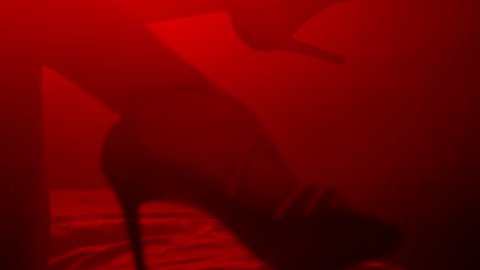 Sexy woman feet in heels shoes. Closeup of sexy female legs in shoes. Erotic concept. Sexy body in red light background
