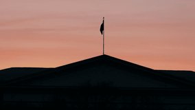 Abstract national flag on the roof of an official building fluttering against the sunset background. (av37943c)
