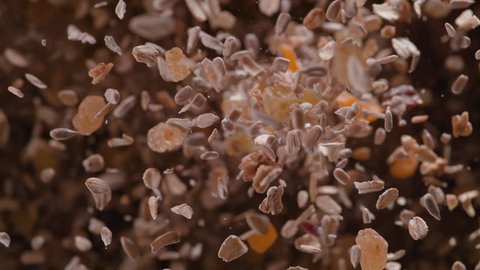 Nuts, seeds and dried fruit fly after being exploded against black background. Shot with high speed camera, phantom flex 4K. Slow Motion.