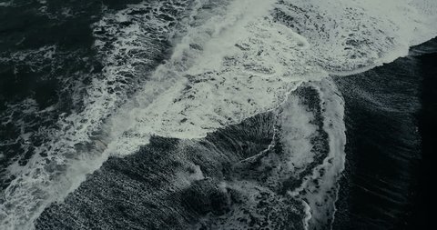 Aerial view of the wild wave with foam coming on the shore of black volcanic beach in Iceland.