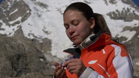 Woman applies sunscreen on her face. High risk to get sunburn high in the mountains
