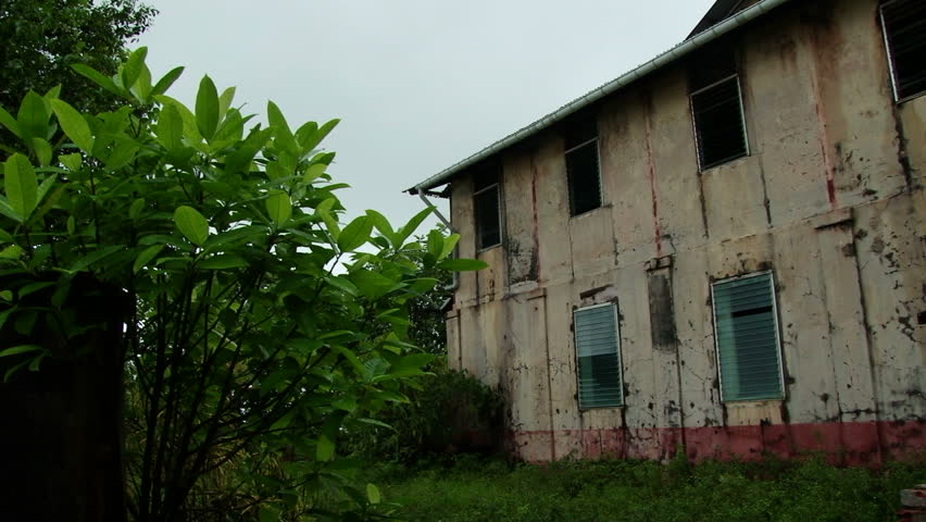 Pan across a derelict administration building on the Devils Island Penal Colony in French Guiana