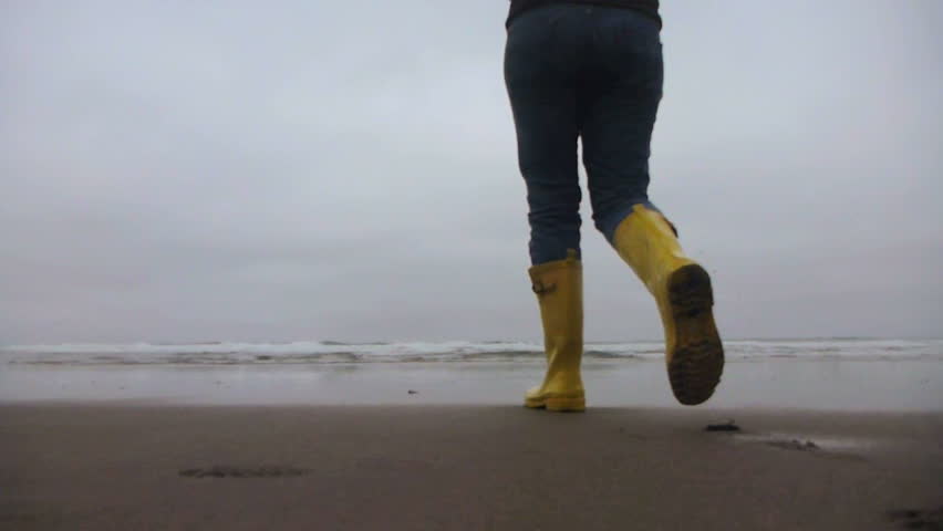 Model released woman walking towards ocean on sandy, Oregon beach.