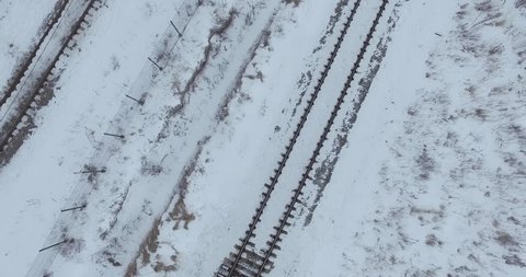 Railroad track top view. Aerial view of empty railroad in winter time. Flying over countryside on a cold snowy winter day.
