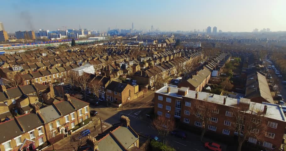 Flying above London surburban houses and apartments aerial view at dawn on sunny day